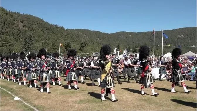 Massed Pipe Bands playing Scotland the Brave on the march during Ballater Highland Games in 2022