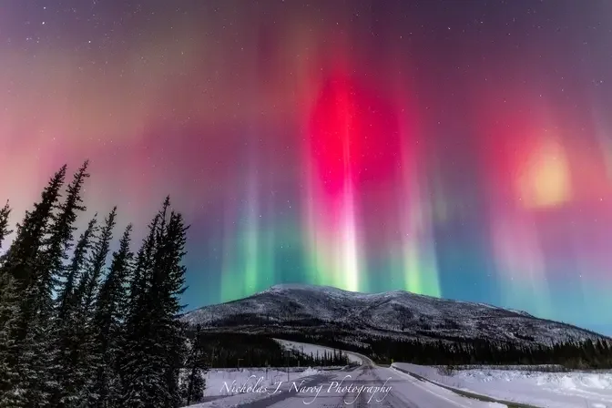 Red auroras light up the sky during a photoshoot.
