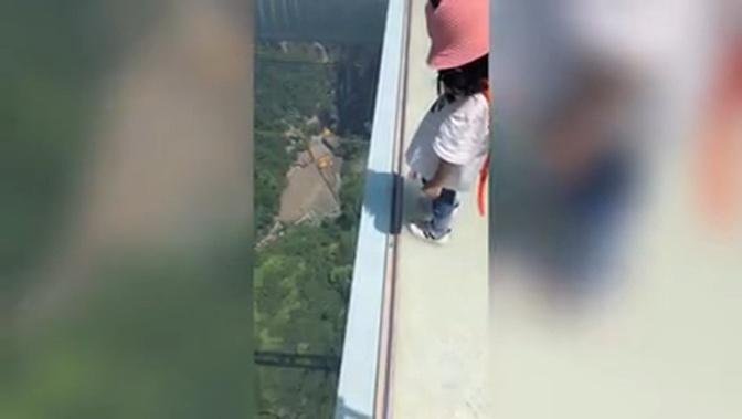 Don't look down! Fearless girl steps onto 260-metre-high glass walkway in China's Zhangjiajie